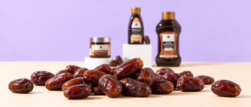 a jar of date spread and a bottle of date syrup standing behind  some glossy  dates